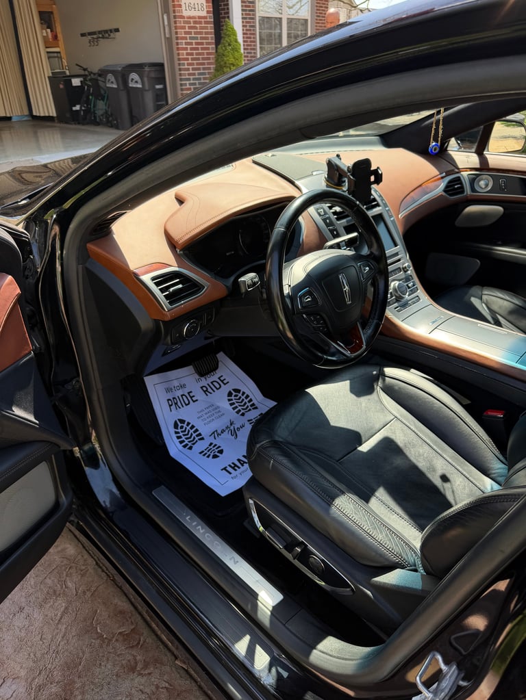 Interior of luxury car with tan and black leather seats, steering wheel, and a white price sticker on the drivers seat
