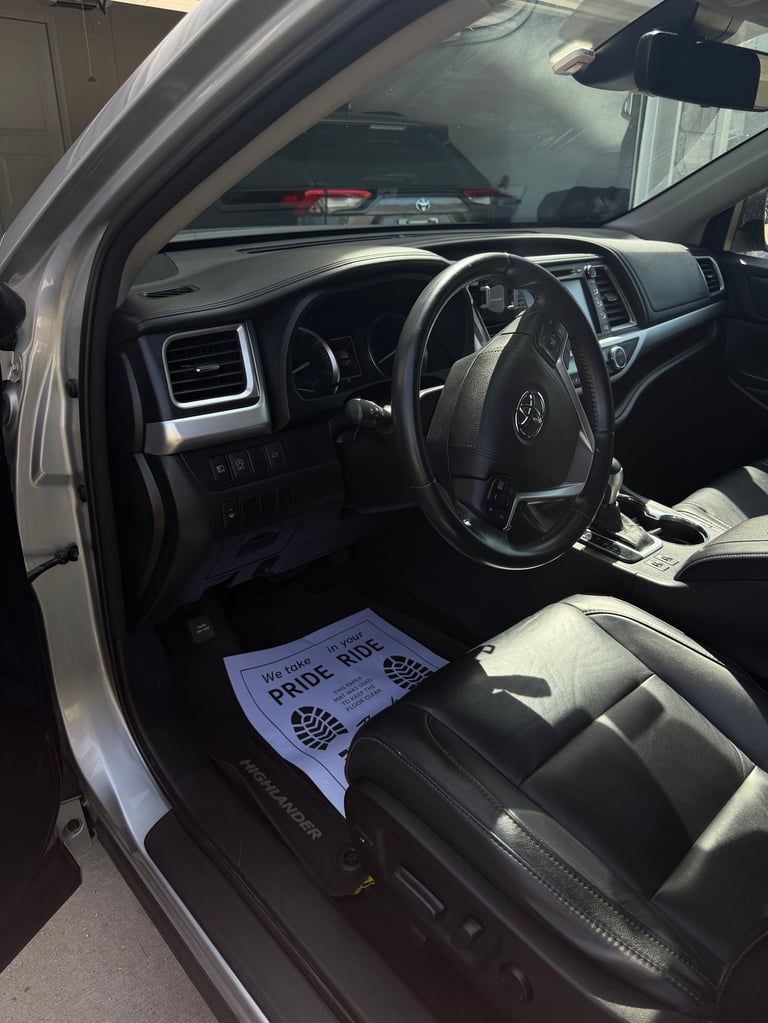 Interior of a silver Toyota truck with black steering wheel, dashboard, and leather seats